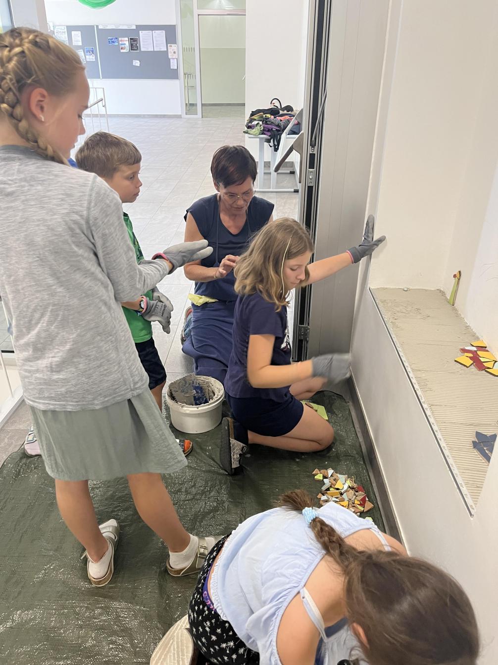 Kinder gestalten ein Mosaik mit Bruchstücken aus Fliesen