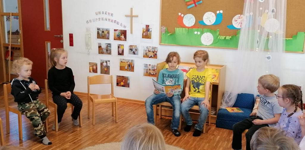 Zwei Schüler lesen den Kindergartenkindern ein Buch vor.